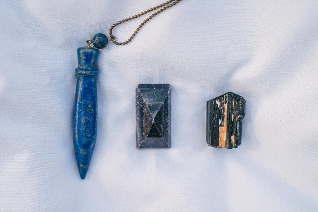Close-up of three healing crystals laid out in a still life arrangement on white fabric.