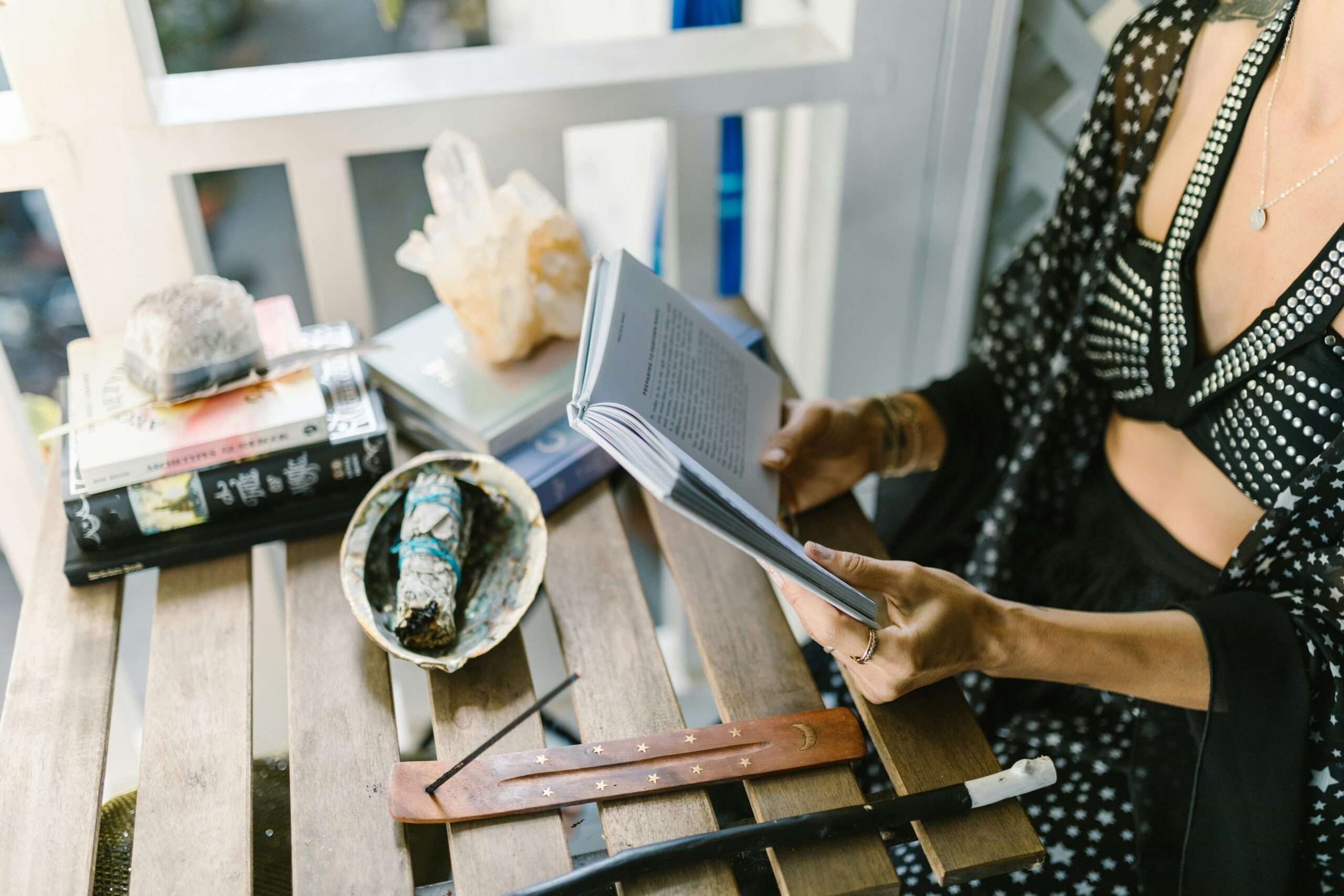 A woman reads surrounded by mystical objects, evoking a magical atmosphere.