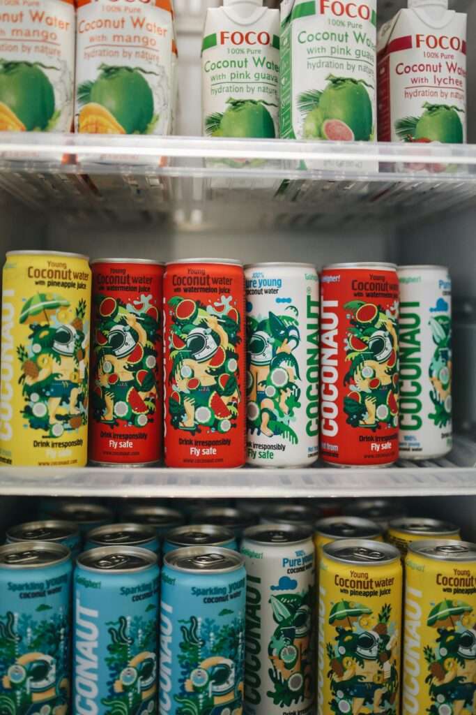 Assorted cans of coconut water neatly arranged in a refrigerator.